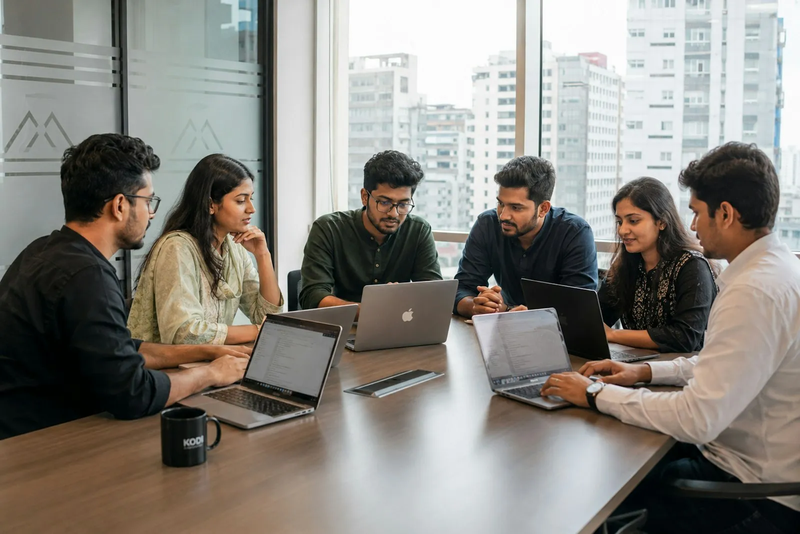 A team reviewing plans together around laptops in a conference room